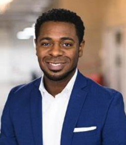 A headshot of Byron Sanders, a male-presenting person, who smiles towards the camera.
