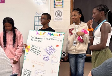 4 children holding a poster they've made about self-management