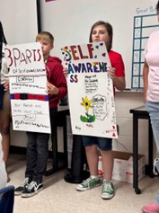 2 children presenting posters they have made.