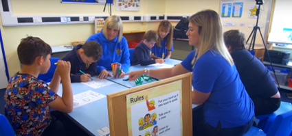 Students working in the classroom with a group of teachers and therapists