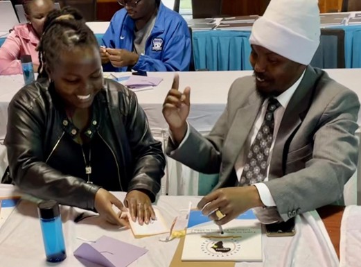 2 people at a table in workshop discussing a paper before. Both look animated, excited.